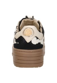 Black and white spotted slip-on sneaker featuring a textured upper, cream accents, and a decorative golden button on the heel.