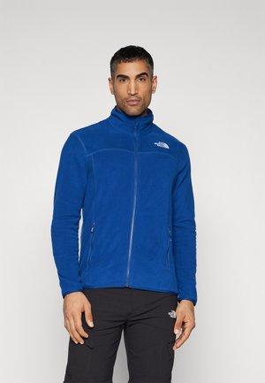 Blaue Fleecejacke mit Reißverschluss, hohem Kragen und zwei vorderen Reißverschlusstaschen. Verfügt über eine glatte Textur und ein Logodetail auf der Brust.