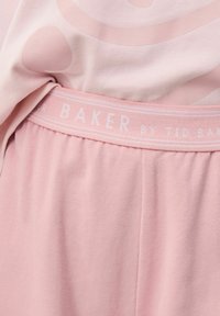 Růžový set domácího oblečení se skládá z topu s kruhovým vzorem a spodní části s měkkým, elastickým pasem označeným "BAKER by Ted Baker."
