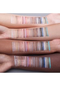 Stalen van make-up in verschillende tinten op drie armen, met metallic, matte en glanzende afwerkingen in lichte tot donkere kleuren, kleurgecodeerd.