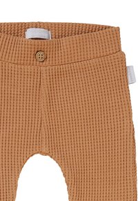 Beige Ripp-Leggings mit einem Holzknopf am Bund und einem elastischen Oberteil. Sie verfügen über eine einzigartige Textur und ein schmal zulaufendes Bein-Design.
