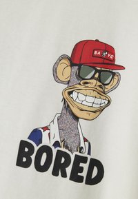 White T-shirt featuring a cartoon gorilla with sunglasses and a red cap, text "BORED" in bold black, and colorful accent patterns on the shirt.