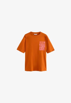 T-shirt en coton orange avec une coupe décontractée, dotée de manches courtes et d'un graphique rose sur la poche gauche en forme de cœur disant "LA NATURE EST L'ÂME".