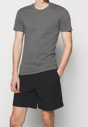Grijs T-shirt met korte mouwen van zachte stof, gecombineerd met zwarte shorts. Het T-shirt heeft een ronde hals en een aansluitend model.