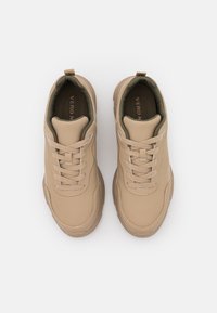 Beige leather sneakers with rounded toe, textured laces, padded collar, and contrasting green lining. Features rubber sole and subtle stitching.
