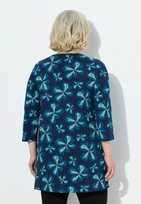 Blommig tunikaklänning i marinblått med stora tealblommönster. Har trekvartslånga ärmar, rundad hals och en avslappnad passform.