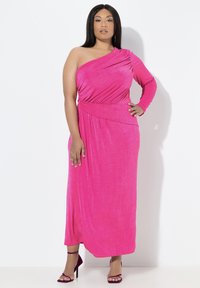 Maxi sukienka na jedno ramię w jaskrawym różowym kolorze, wykonana z miękkiej, elastycznej tkaniny, z drapowanymi detalami i dopasowaną talią. Do kompletu dopasowane, paskowe szpilki.