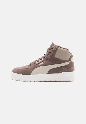 High-top sneakers made of brown suede and beige synthetic material, featuring white rubber soles, prominent PUMA logo, and gold accents.