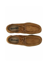 Braune Wildleder-Slipper mit runder Spitze, Kontrastnähten und einer flachen Gummisohle. Mit einem Schnürakzent an der Vorderseite. Marke: Bianc.
