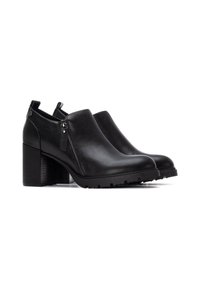 Botas de cuero negro hasta el tobillo con cremallera lateral, acabado texturizado, tacón grueso y suela de goma que presenta un patrón de tracción para mayor agarre.