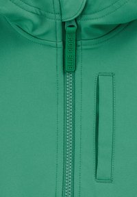 Giacca verde con zip, realizzata in un tessuto morbido. Presenta una zip a tutta lunghezza con un tirante marchiato e una tasca laterale.