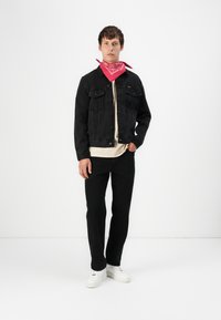 Black denim jacket with two front pockets, beige shirt, black pants, and white sneakers. Red bandana tied around the neck.