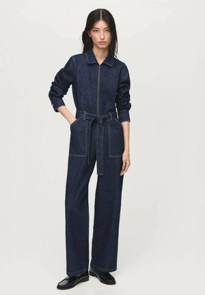 Denim jumpsuit with a zip front, collar, and wide legs; features a fabric belt and contrasting stitching. Color: dark blue.