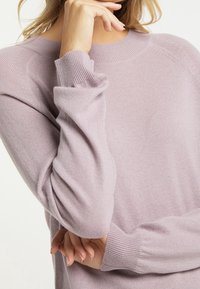 Jasnofioletowy sweter wykonany z miękkiego dzianiny. Posiada ribbowany okrągły dekolt i długie rękawy z ribbowanymi mankietami. Subtelny detal teksturowy.