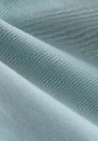 Tissu bleu clair avec une texture lisse, présentant un motif tissé délicat et un éclat subtil, mettant en valeur des plis doux et un drapé léger.