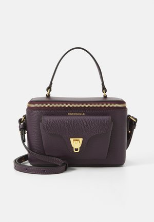 Borsa a tracolla in pelle viola con forma strutturata, accessori in oro, chiusura con zip superiore e tasca frontale con chiusura a scatto. Include una tracolla regolabile.