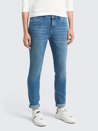 Jean bleu clair à coupe slim, avec dégradé, design à cinq poches et ourlets retroussés, associés à des baskets blanches. En matériau en coton.