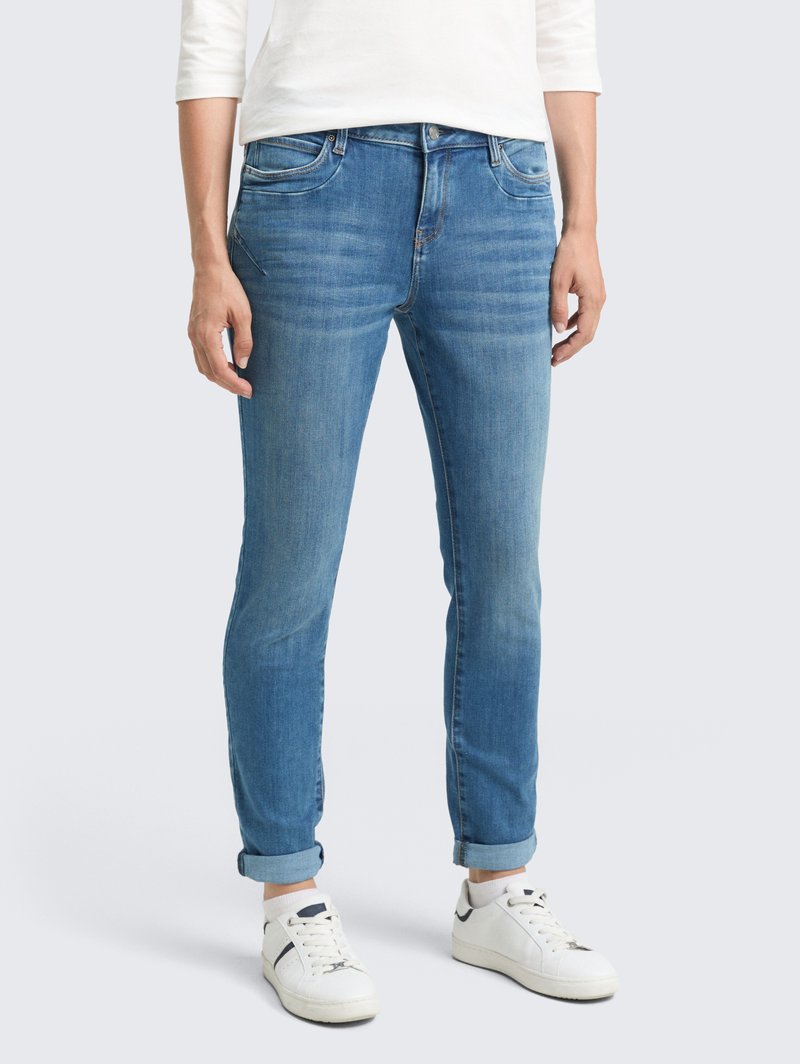 Jean bleu clair à coupe slim, avec dégradé, design à cinq poches et ourlets retroussés, associés à des baskets blanches. En matériau en coton.
