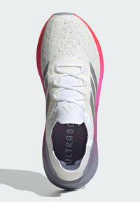 Bílé běžecké boty s texturovaným síťovaným svrškem, šedými akcenty a gradientní podrážkou přecházející z růžové do fialové. Obsahují šest tkaniček a pánev se značkovou vložkou.