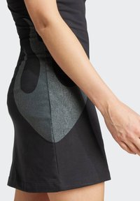 Svart figurnära klänning med ett texturerat grått abstrakt mönster på sidan. Mjuk bomullsmaterial med en slät yta. Ärmlös design.