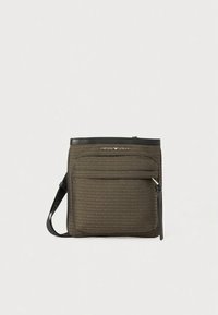 Rjava teksturirana torbica čez ramo z zadrgo, sprednjim žepom in naramnim trakom. Na sprednji strani ima izrezljan logotip.