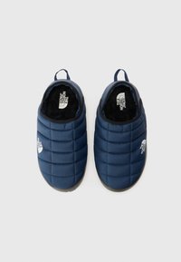 Chaussons rembourrés bleu marine avec texture matelassée, doublure noire et semelles en caoutchouc. Possède un logo sur le côté et des languettes pour un enfilage facile.