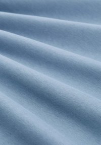 Lichtblauwe stof met een gladde textuur, met zachte plooien die diepte en subtiele schaduwen creëren. Katoen of katoenmix materiaal.