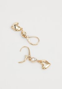 Boucles d'oreilles en forme de cœur doré avec des accents en cristal et un fermoir à levier, mettant en valeur une texture lisse et une finition brillante.
