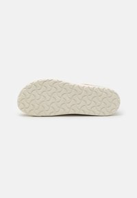 Sål av en teksturert, bølgete mønster; laget av gummi; kremfarget; avrundede kanter; viser holdbarhet og friksjonsdesign.