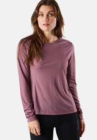 Pitkähihainen urheilupaita pehmeässä mauvenvärisessä kankaassa, jossa on tekstuuri. Siinä on pyöreä pääntie ja istuva malli, joka sopii erinomaisesti urheiluun.