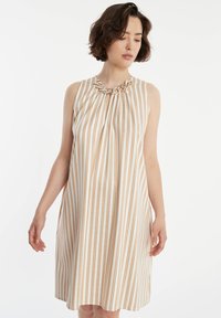 Robe sans manches légère avec des rayures verticales beige et blanches, présentant un col froncé et une silhouette A-line ample.