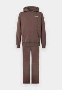 Brązowa bawełniana bluza z kapturem z kieszenią kangurką i ściągaczami na rękawach, w połączeniu z pasującymi brązowymi spodniami. Prosty design i miękka tekstura.