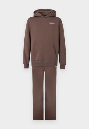 Brauner Baumwollhoodie mit Kängurutasche und gerippten Bündchen, kombiniert mit passenden braunen Hosen. Einfaches Design und weiche Textur.