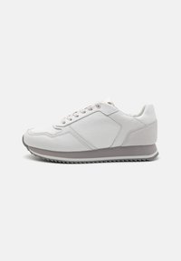 White sneaker with a smooth leather upper, textured panels, gray accents, and a ridged rubber sole. Laced design with subtle stitching.