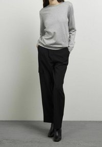 Grijze lange mouw top gecombineerd met zwarte cargobroek met zijzakken, gemaakt van zachte stof met een relaxte pasvorm, aangevuld met enkellaarzen.