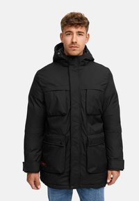 Parka nera isolata con cappuccio, chiusura anteriore a snap, due grandi tasche con patta e polsini regolabili. Tessuto testurizzato e accento con logo arancione.