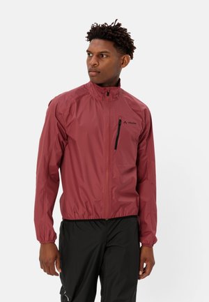 Giacca leggera rossa con colletto alto, tasca sul petto con zip, polsini elasticizzati e design elegante. Presenta un piccolo logo sul lato sinistro.