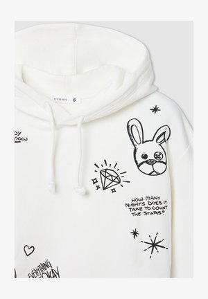 La felpa bianca presenta grafiche nere, tra cui un coniglio, un diamante e del testo. I lacci del cappuccio mostrano una texture di tessuto morbido.