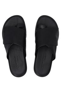 Sandales à glissière en cuir noir avec des brides superposées, semelle plate et logo en relief sur la semelle intérieure. Texture lisse et design minimaliste.