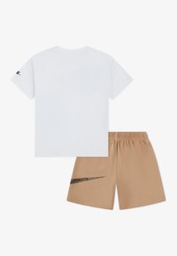 Λευκό βαμβακερό μπλουζάκι με κοντά μανίκια, με μαύρο λογότυπο στο αριστερό μανίκι. Μπεζ σορτς με ελαστική μέση και μαύρη διακοσμητική λεπτομέρεια.