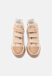 Μπεζ πάνινα παπούτσια ψηλού πάτου με τρεις λουράκια βέλκρο, λαστιχένιες μύτες, λευκή εσωτερική επένδυση και την επιγραφή "ROOAAR" κεντημένη με πορτοκαλί στο πάνω λουράκι.