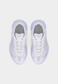 Ζευγάρι λευκών και ανοιχτόμωβ αθλητικών παπουτσιών Lacoste με υλικό από δίχτυ και δέρμα, φαίνεται από ψηλά σε απλό λευκό φόντο.