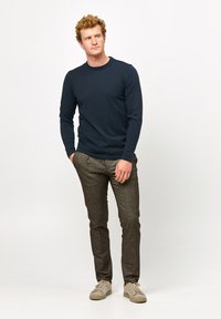 Marineblå langærmet skjorte parret med mørke teksturerede bukser og sneakers i lys farve, med et enkelt design uden mønstre eller udsmykninger.