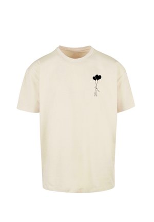 Krémové tričko vyrobené z bavlny, s čiernou grafikou postavy držacej dva balóniky v tvare srdca na ľavej strane.