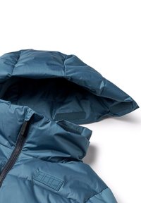 Sininen puhallettava takki hupulla, joka on varustettu teksturoidulla, kiiltävällä pinnalla, edessä vetoketjulla ja tarranauha-yksityiskohdilla kaulan alueella.