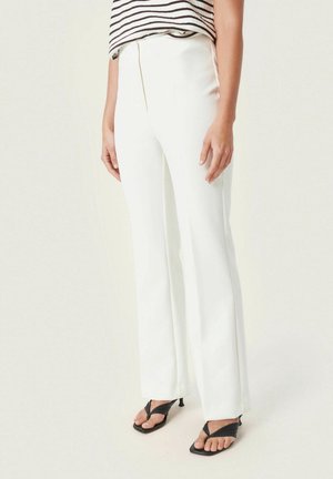 Person wearing high-waisted white straight-leg trousers paired with black strappy heeled sandals and a striped top.