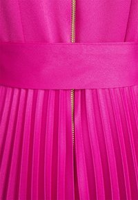 Robe fuchsia avec jupe plissée, dotée d'une large ceinture et d'une fermeture éclair dorée centrale. Tissu lisse avec une texture brillante.