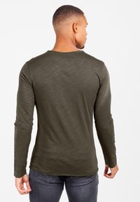 Olivengrünes Langarmshirt mit rundem Halsausschnitt und weicher Textur, das einen leicht abgerundeten Saum und enganliegende Ärmel aufweist.