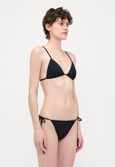 Black bikini set featuring a ribbed texture, triangular top with thin straps, and tie-side bikini bottoms with gold hardware accents.
