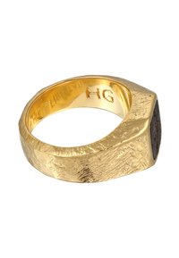 Bague en or avec une surface texturée et une forme hexagonale. Présente un accent de pierre sombre et des détails gravés à l'intérieur de l'anneau.